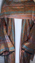 Patterned shawl draped over a person against a white background